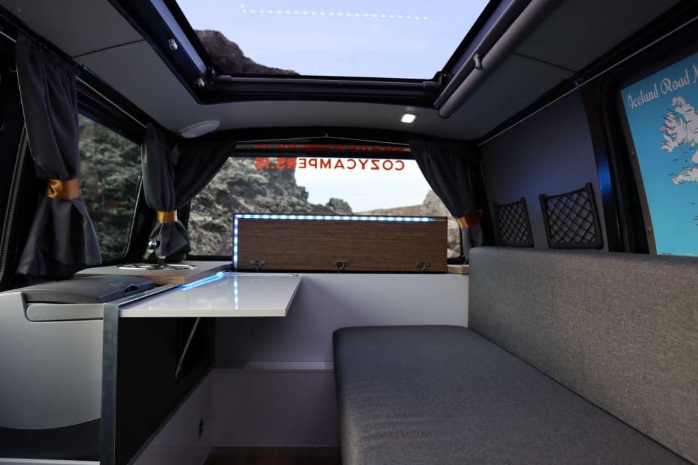 Looking up through the full-width panoramic sky roof of the Highlander II, open above the rear dinette with an Iceland road map on the side wall