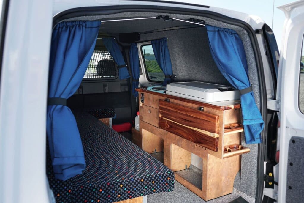 Side door open on the Easy Ranger EXP showing the wooden galley unit, cool box and blue curtains