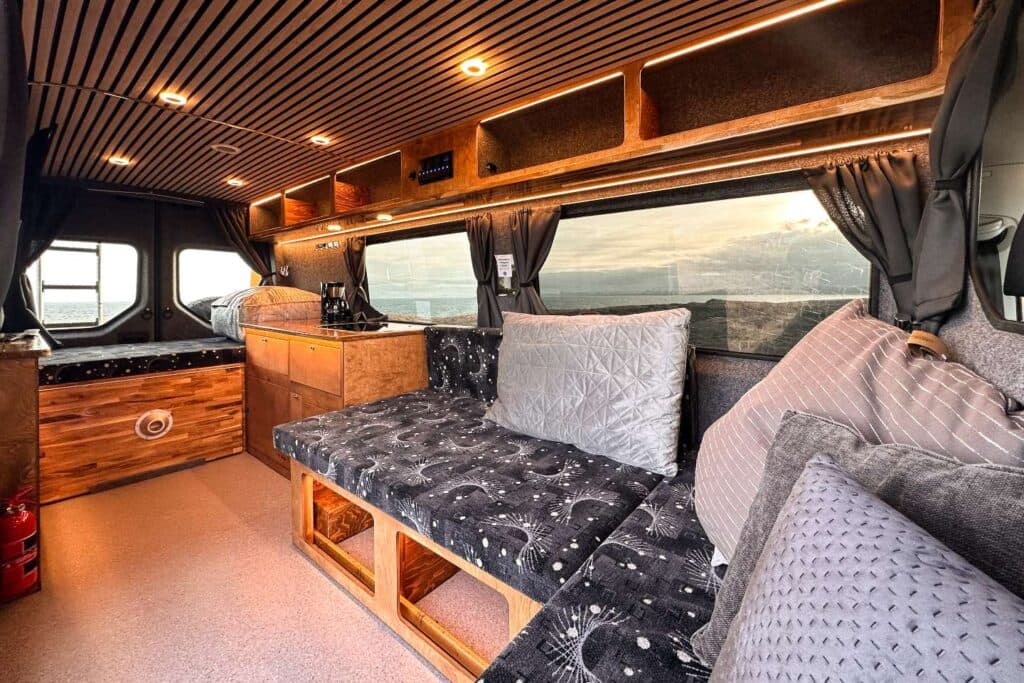 Interior of the Easy Luxury with an L-shaped bench bed, slatted wood ceiling and overhead lockers
