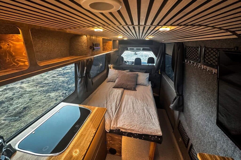 Interior of the Easy Monster with a slatted wood ceiling, made-up bed and a wooden counter with a covered sink