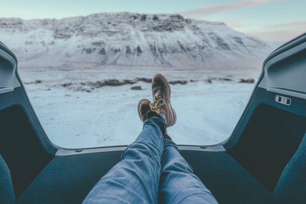 View from inside the Tesla with feet up on the dashboard, looking out at a snow-covered mountain