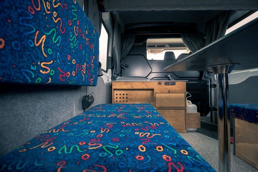 Interior of the Easy Big looking forward over the patterned bench seats towards the wooden kitchen unit