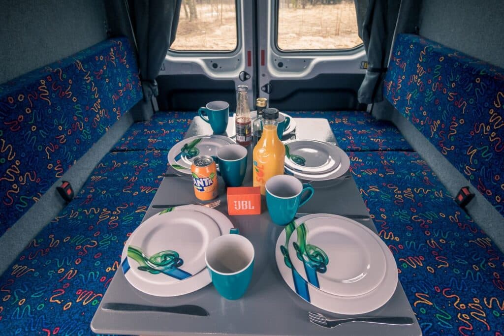 Table set with plates, mugs and drinks between two patterned bench seats inside the Easy Big
