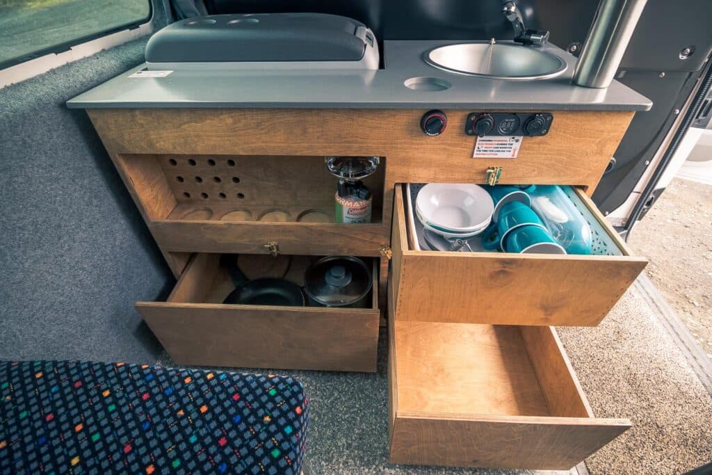Galley drawers pulled out in the Easy Clever EXP showing stacked crockery, with the sink and worktop above