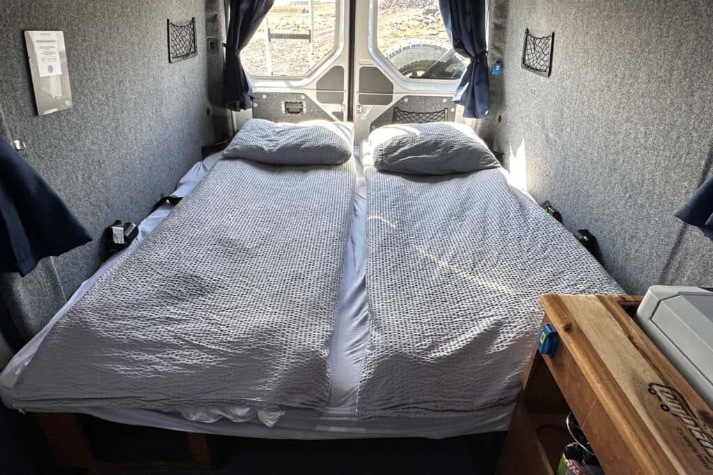 Double bed made up with grey duvets inside the Easy Viking EXP, looking towards the rear doors