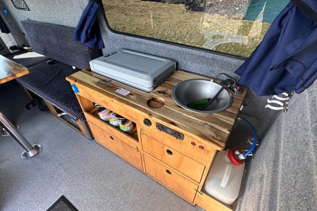 Galley in the Easy Viking EXP with a cool box, stainless sink, wooden drawers and navy curtains