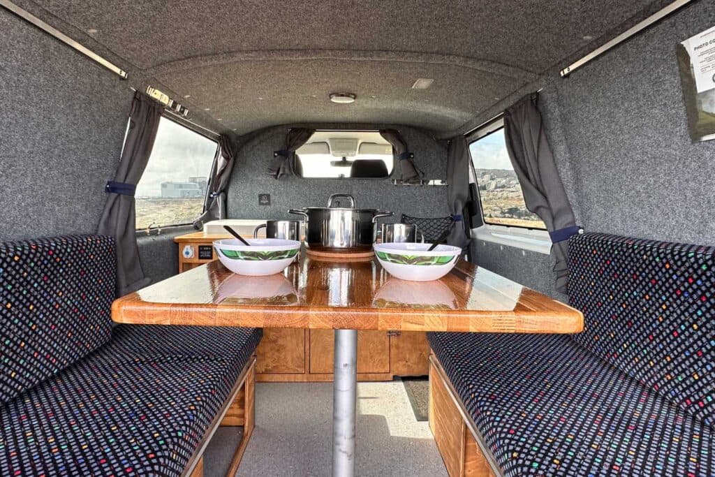 Bench seats facing a wooden table set with two bowls and a cooking pot inside the Easy Fun